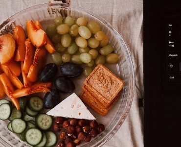 A delightful snack plate with fruits, cheese, and a laptop for a healthy lifestyle.